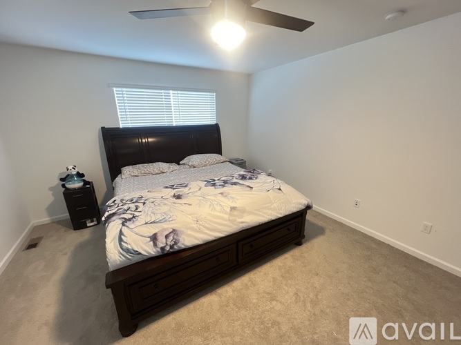 A bedroom with a large bed and a small table with a lamp on it.