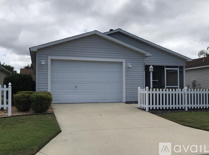 A house with a grey garage door and a white picket fence.