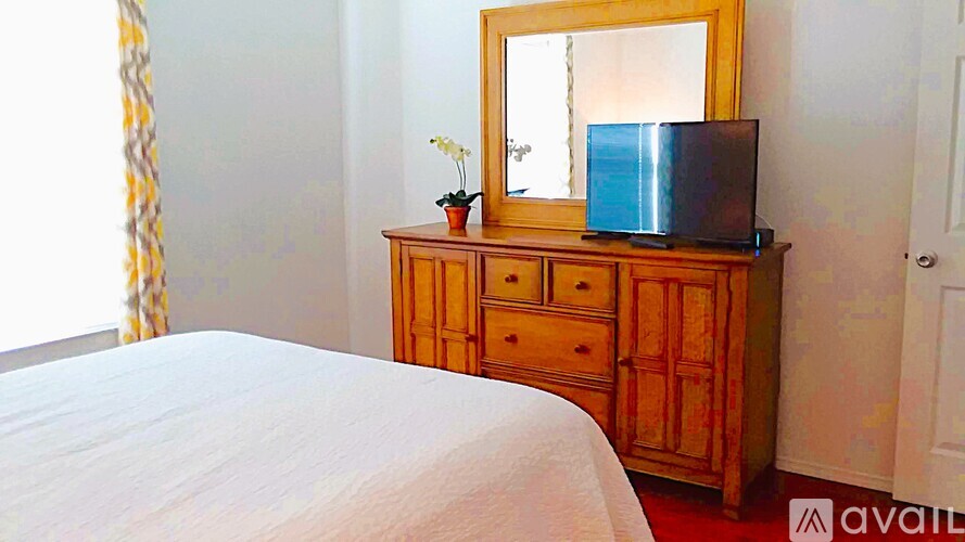 A bedroom with a bed, a dresser with a mirror and a television on top.