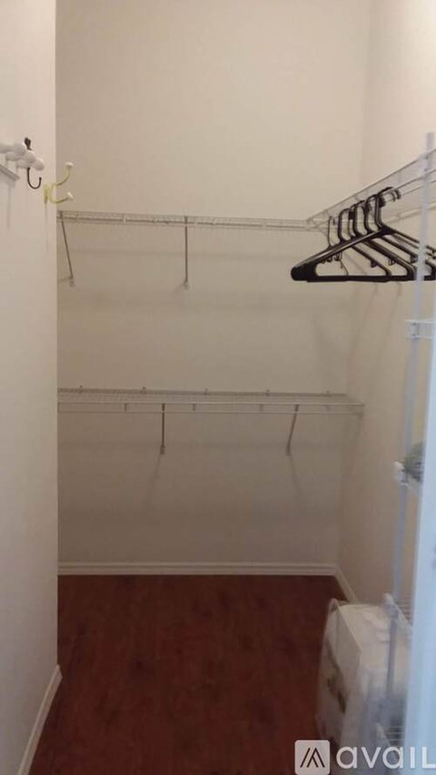 A small, empty closet with a wooden floor.