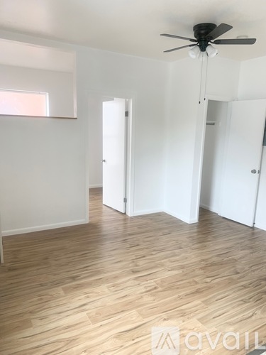A room with a ceiling fan and wooden flooring.