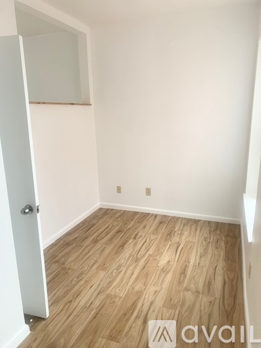 A room with a white door and wooden flooring.