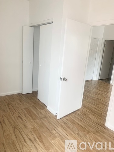 A room with a white door and wooden flooring.