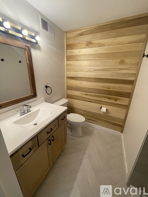 A bathroom with a wooden wall and a white sink.