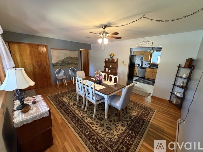 A dining room with a rug, chairs, and a table.