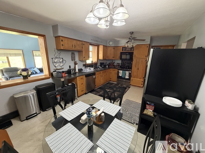 A kitchen with a black refrigerator and a dining table with chairs.
