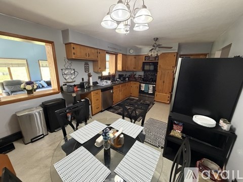 A kitchen with a black refrigerator and a dining table with chairs.
