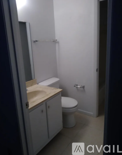 A bathroom with a toilet, sink, and cabinet.