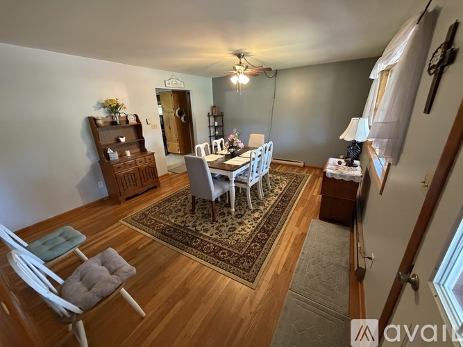 A dining room with a table set for four and chairs around it.