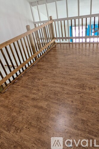 A room with wooden flooring and a balcony railing.