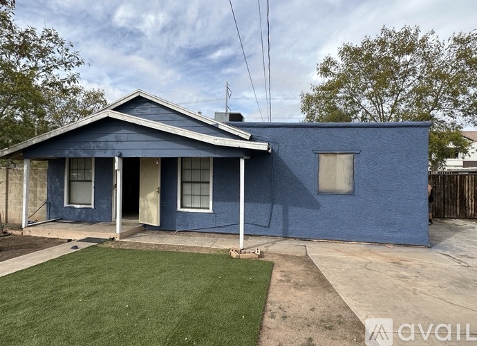 A blue house with a white fence and a green lawn.