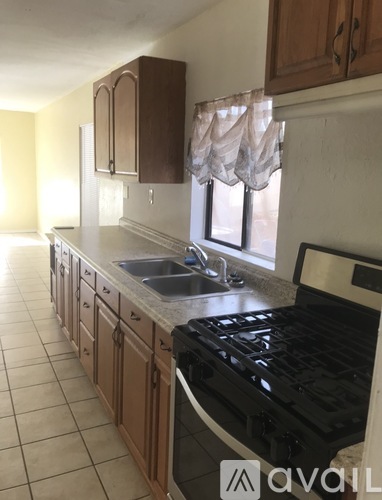 A kitchen with a black stove top oven and wooden cabinets.