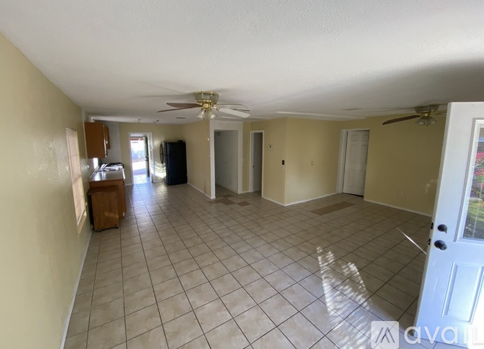 A spacious room with a fan and tiled flooring.