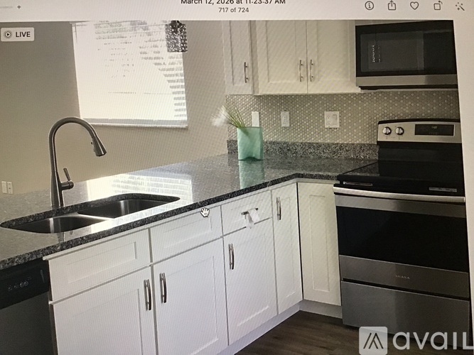 A kitchen with white cabinets and a black countertop.