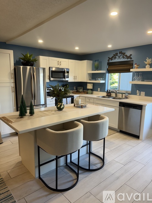 A kitchen with a white island and two chairs.