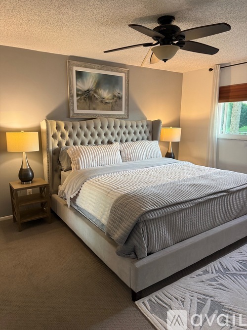 A bedroom with a large bed and a ceiling fan.