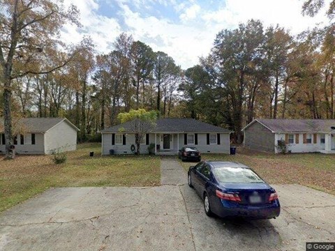 A car is parked in a driveway in front of a house.
