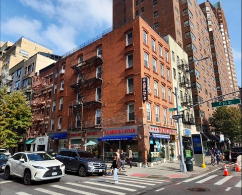 A street view of a city with cars, buildings, and a pedestrian crossing.