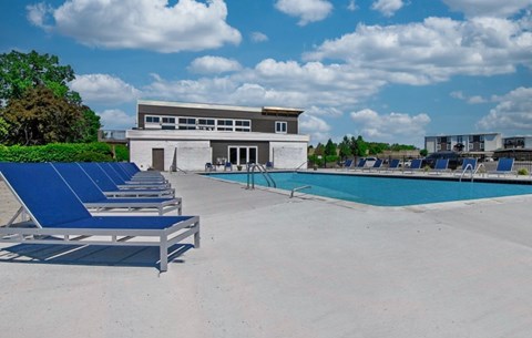 A pool area with sun loungers and a building in the background.