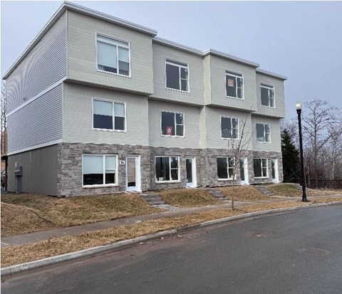 A grey apartment building with a white door and windows.