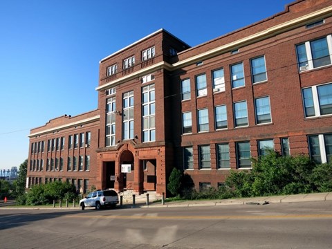 A large red brick building with a car parked in front.
