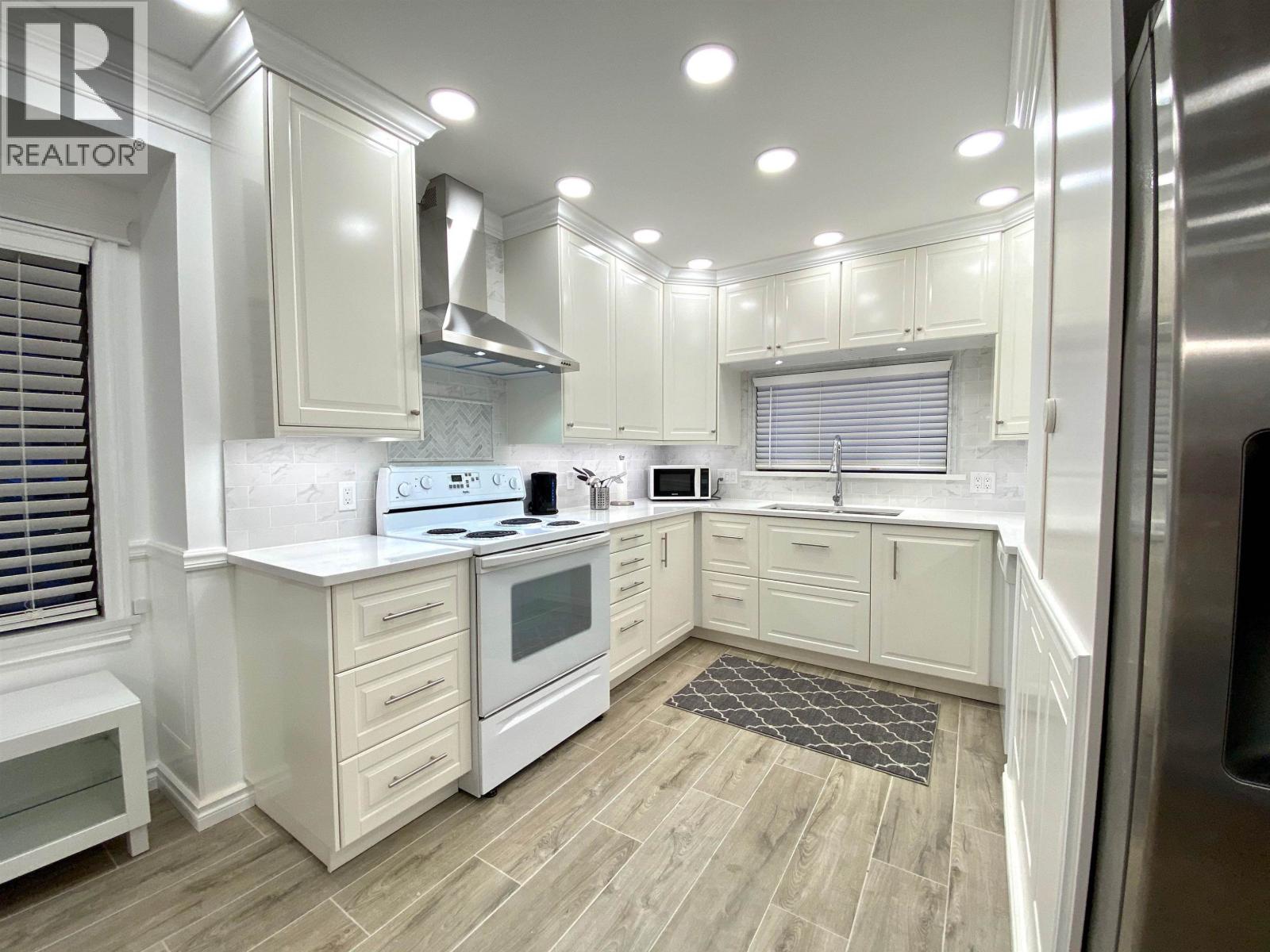 A kitchen with white cabinets and a wooden floor.