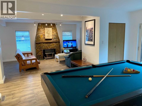 A pool table is in the middle of a living room with a fireplace and a TV.