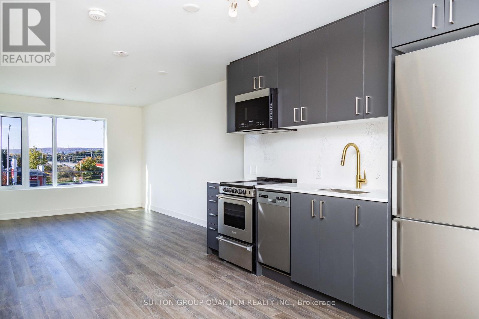 A kitchen with a refrigerator, oven, and microwave.