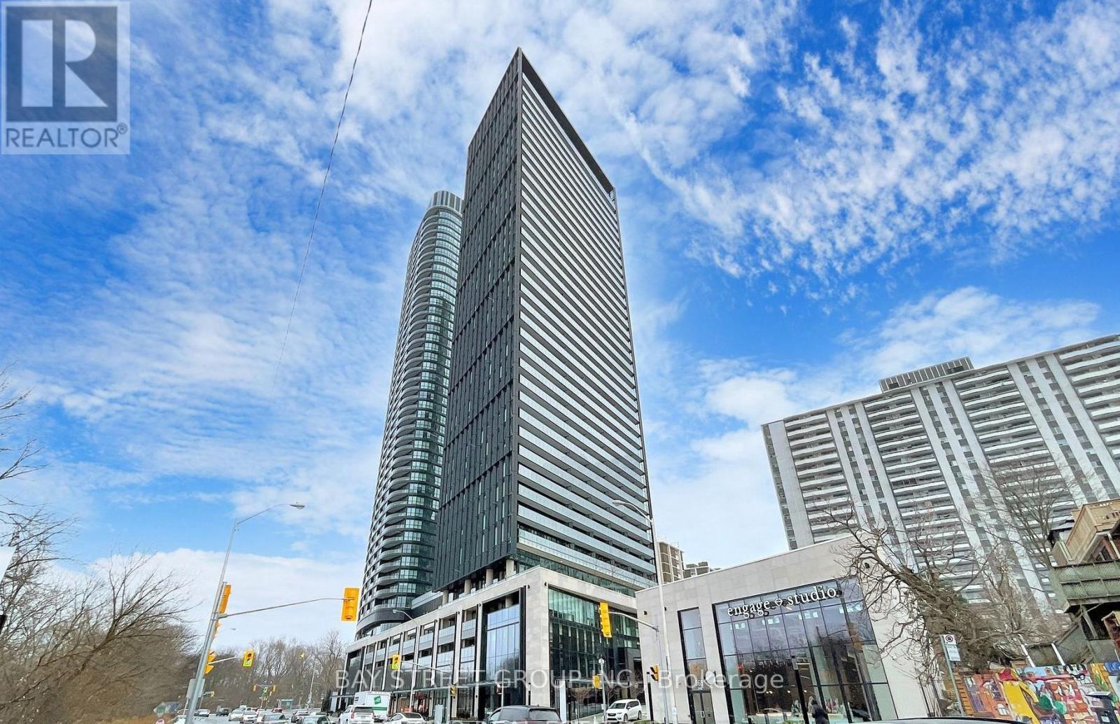 A tall building with a glass facade stands in front of other buildings.