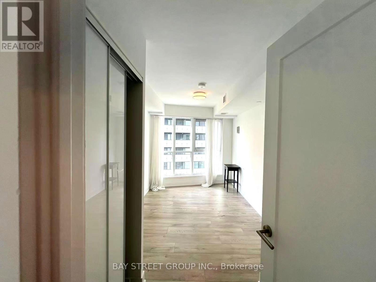 A hallway with a door on the left and a balcony on the right.