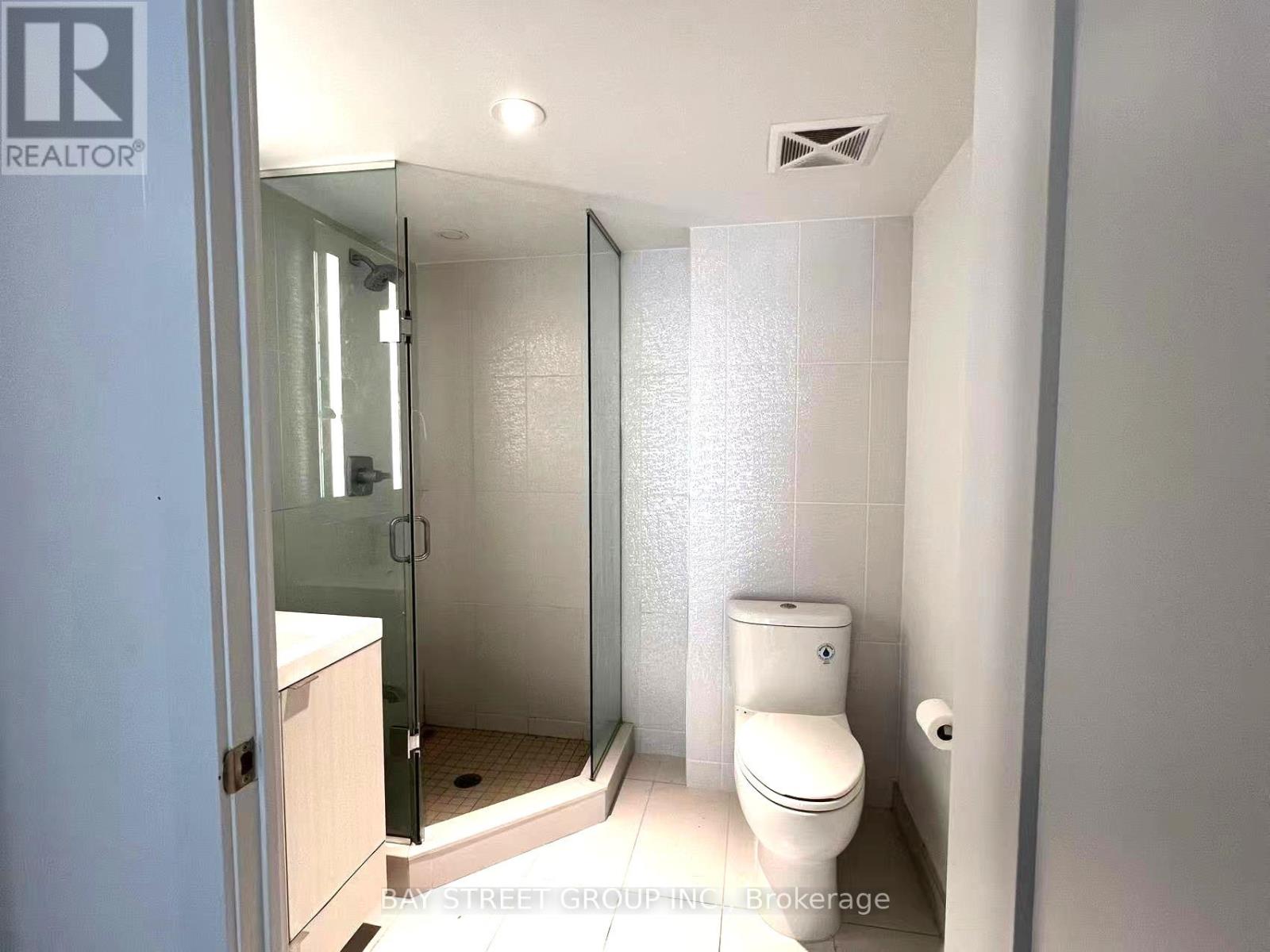 A white toilet in a small bathroom with a glass shower door.
