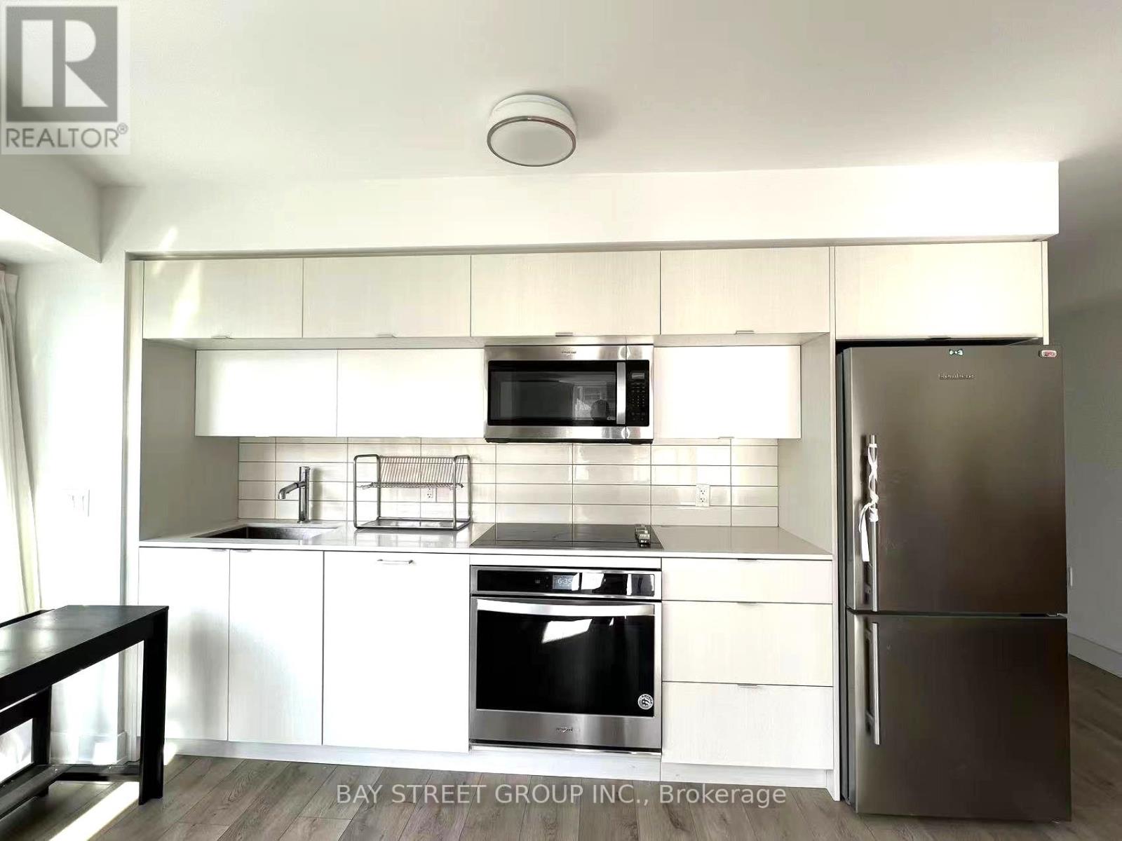 A modern kitchen with white cabinets and stainless steel appliances.
