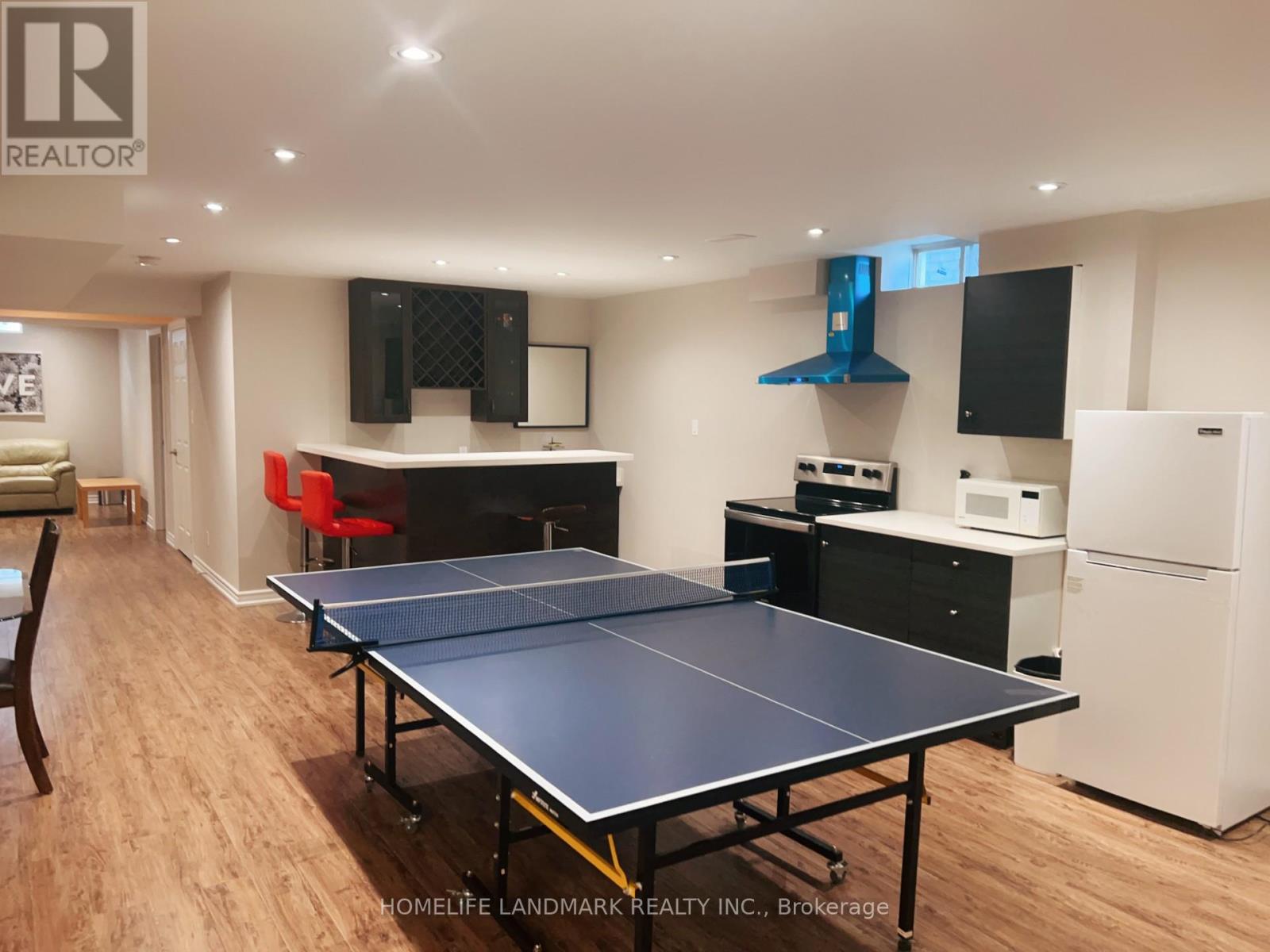 A ping pong table is in the middle of a room with a white refrigerator.