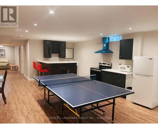 A ping pong table is in the middle of a room with a white refrigerator.