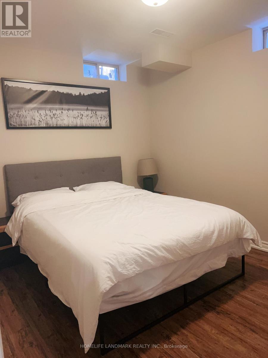 A bedroom with a bed, lamp, and picture on the wall.