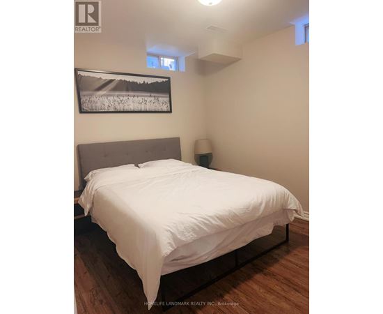 A bedroom with a bed, lamp, and picture on the wall.