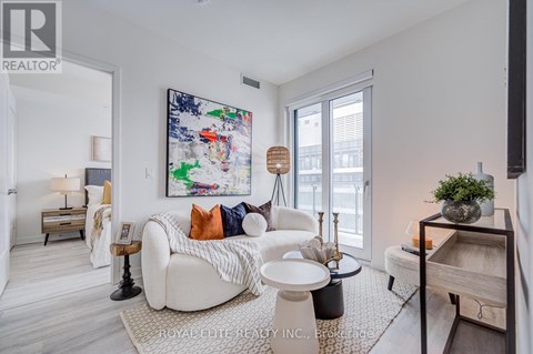 A living room with a white couch and a large abstract painting on the wall.