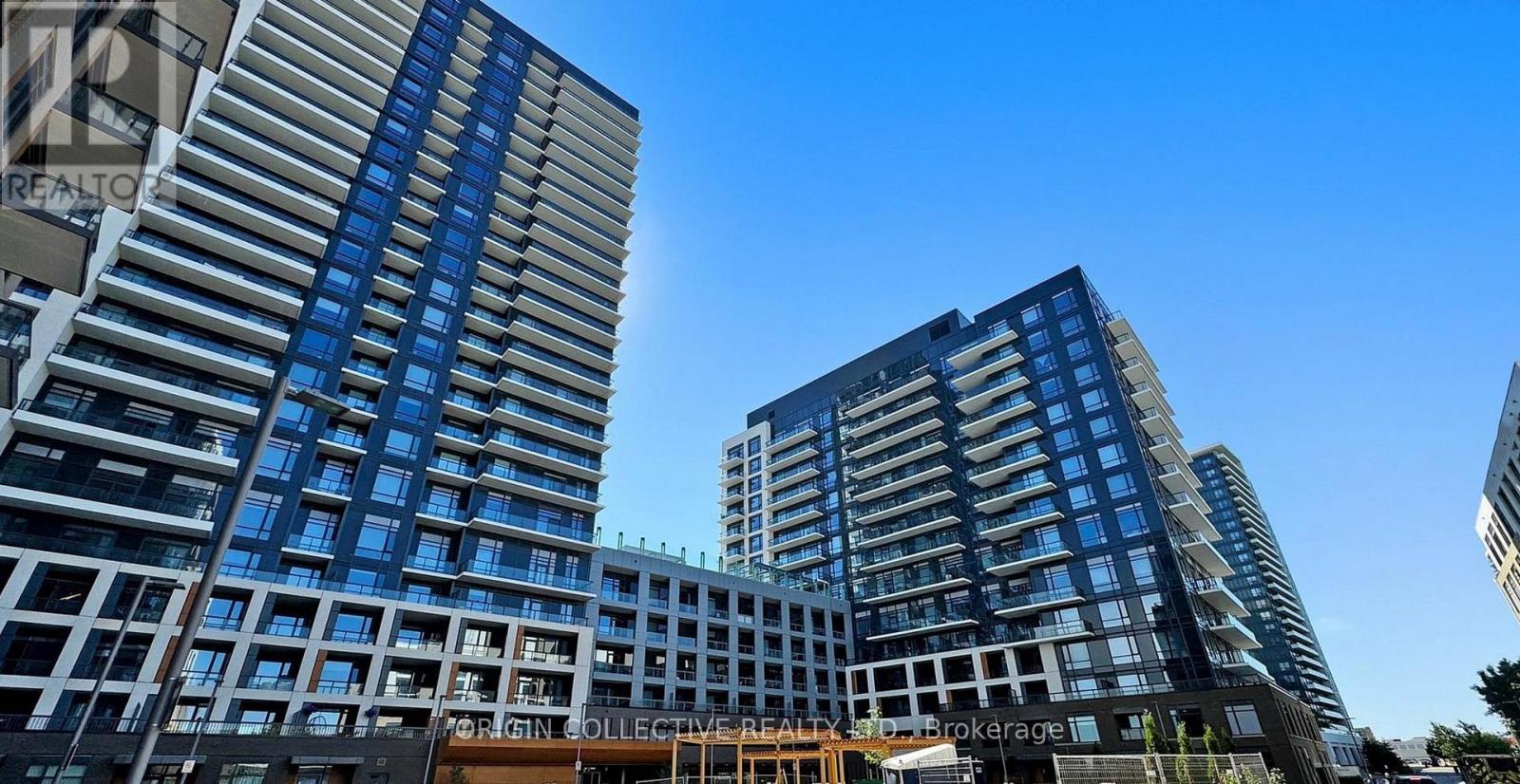 A modern building with a glass facade stands tall against a clear sky.
