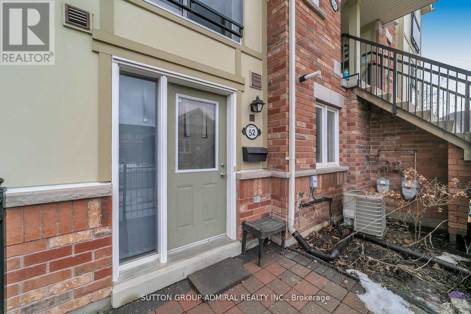 A small balcony with a table and chairs is attached to a brick house.