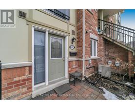 A small balcony with a table and chairs is attached to a brick house.