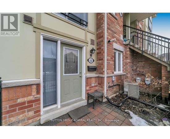 A small balcony with a table and chairs is attached to a brick house.