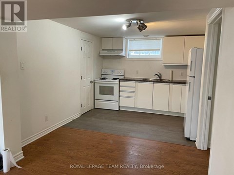 A kitchen with white cabinets and a wooden floor.