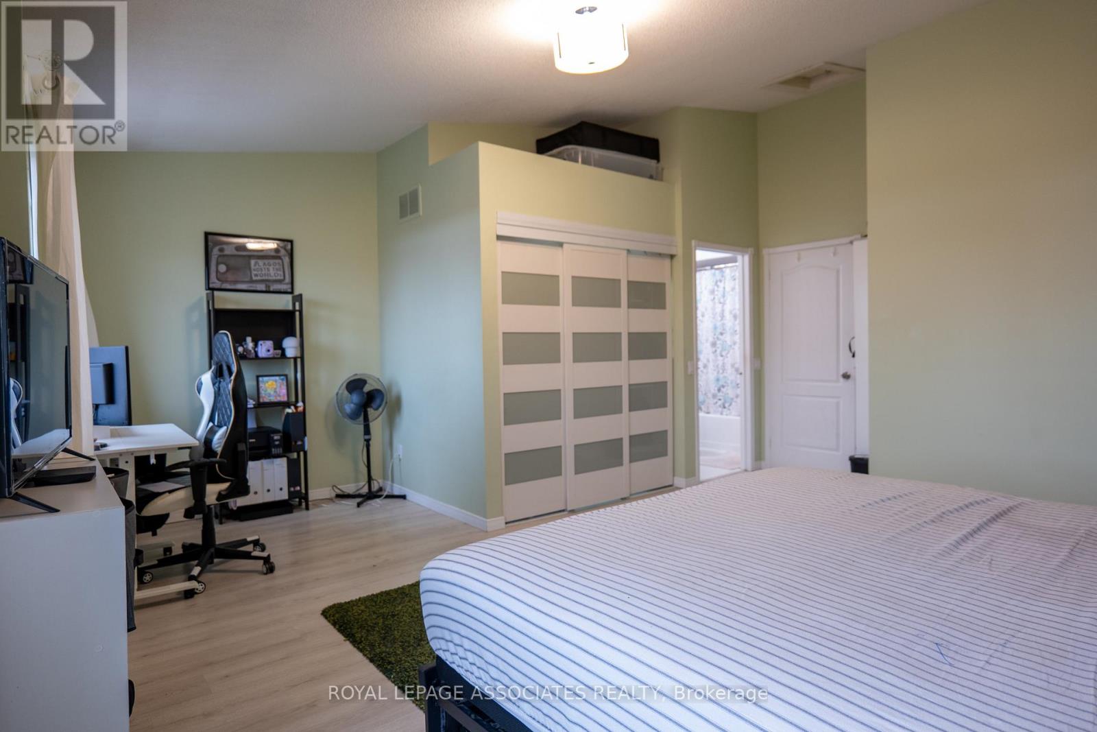 A bedroom with a bed, desk, and exercise equipment.