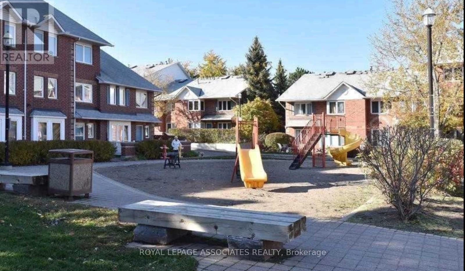 A playground with a yellow slide in the middle of a grassy area.