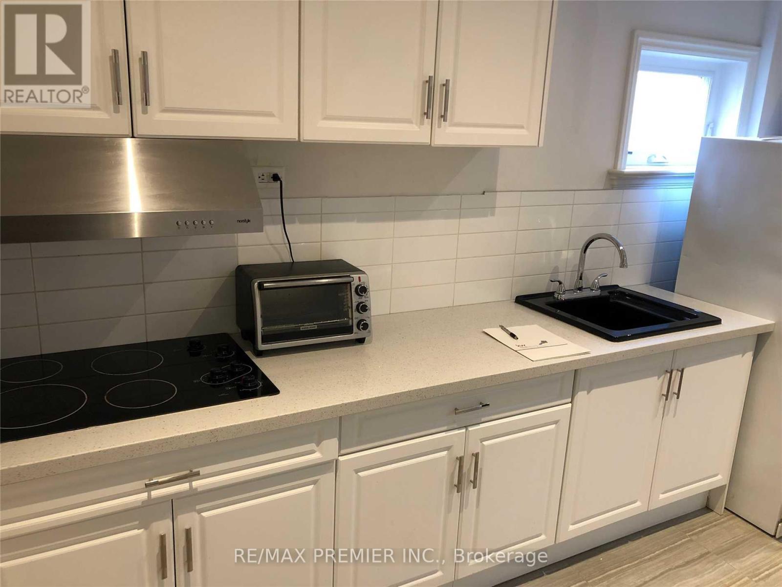A kitchen with white cabinets and a black stove top.