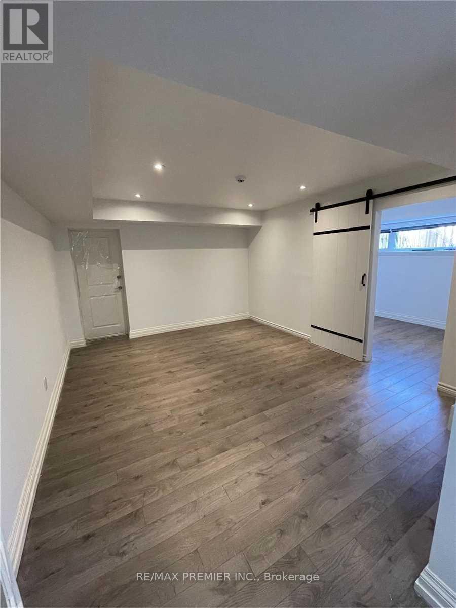 A room with wooden flooring and white walls, with a door on the right side.