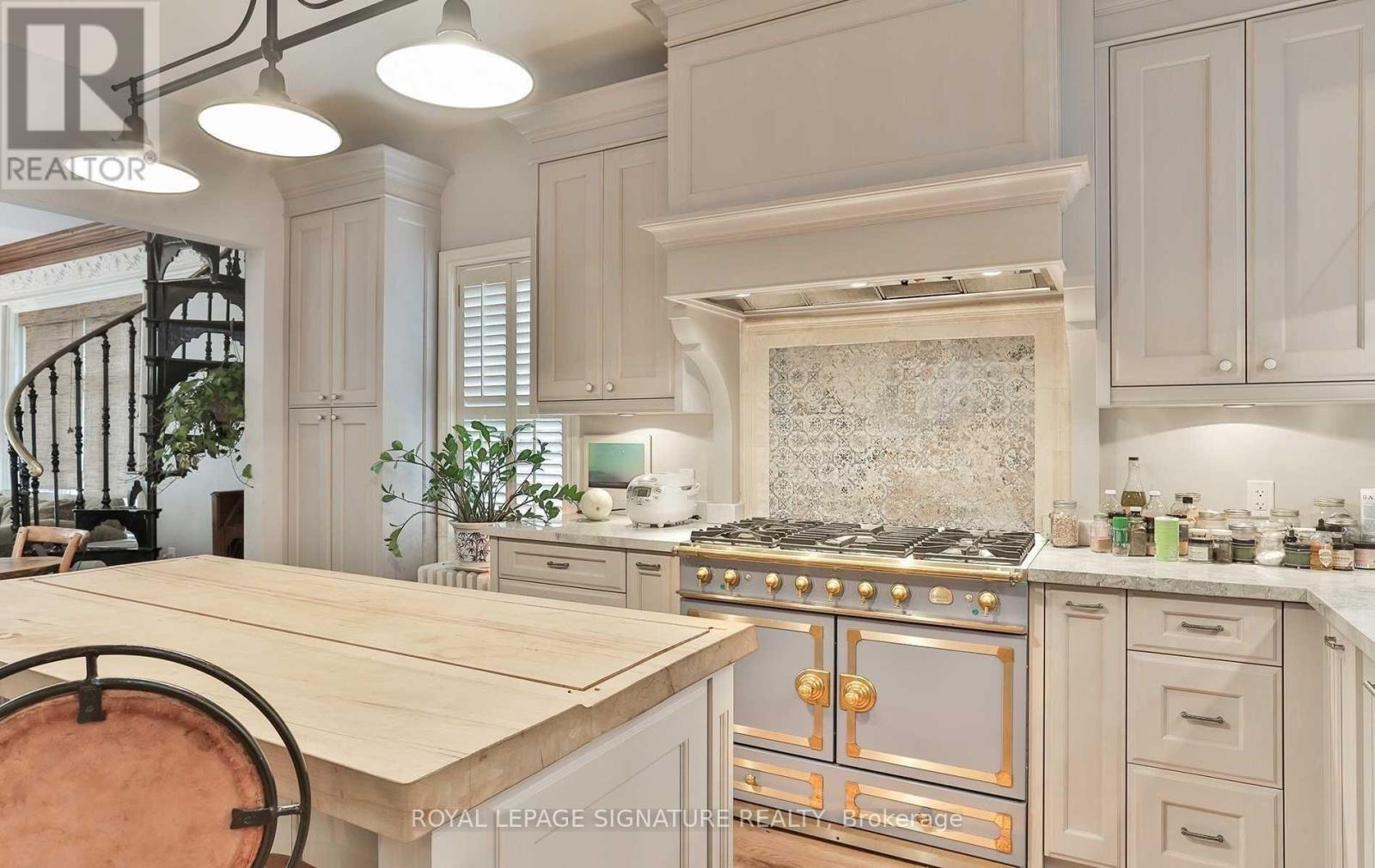 A kitchen with a wooden table and a stove with a gold handle.