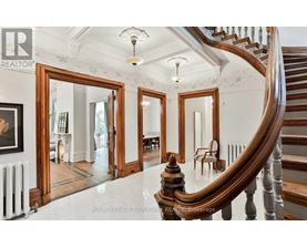 A spacious foyer with a curved staircase and a large mirror.