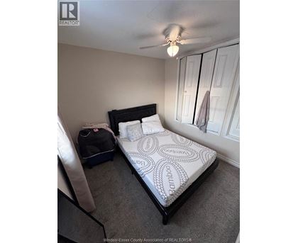 A bedroom with a bed, a suitcase, and a bag on the floor.