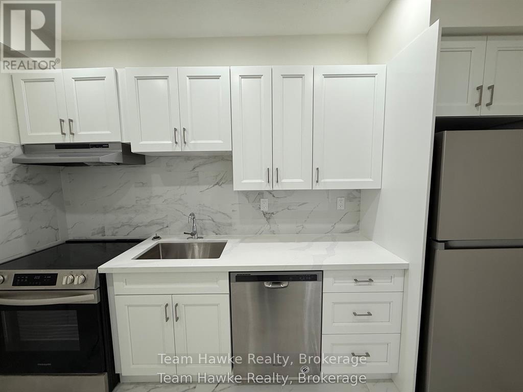 A kitchen with white cabinets and a marble backsplash.